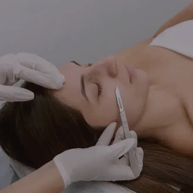 A dermaplaning blade held flat against the skin